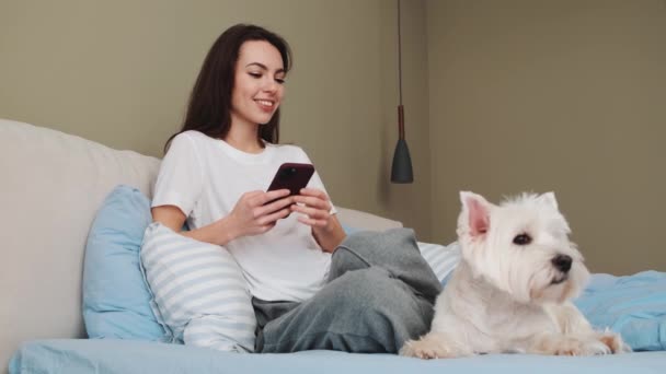 Una Ragazza Positiva Accarezza Suo Cane Seduto Nel Letto Parla — Video Stock