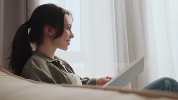 Una Vista Lateral Una Chica Positiva Está Leyendo Libro Sentado — Vídeos de Stock