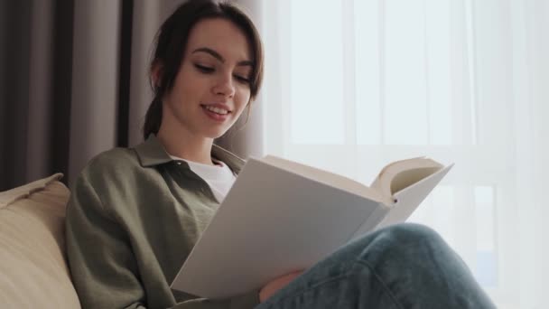 Una Ragazza Sorridente Sta Leggendo Libro Seduta Casa — Video Stock