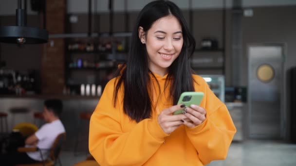 Positive Woman Orange Hoodie Typing Something Phone While Standing Cafe — Video