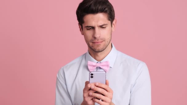 Jovem Chocado Usando Laço Está Olhando Para Seu Smartphone Isolado — Vídeo de Stock