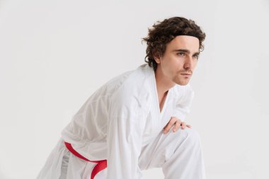 Kendine güvenen genç karateci ısınıyor, beyaz arka planda izole edilmiş.