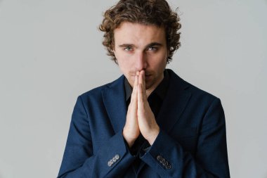 Ceketli, kendine güvenen, avuçlarını bir arada tutan yakışıklı bir adam beyaz arka planda izole edilmiş.