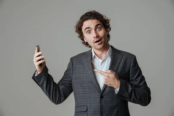 Hombre Sorprendido Auriculares Sosteniendo Señalando Con Dedo Teléfono Móvil Aislado — Foto de Stock