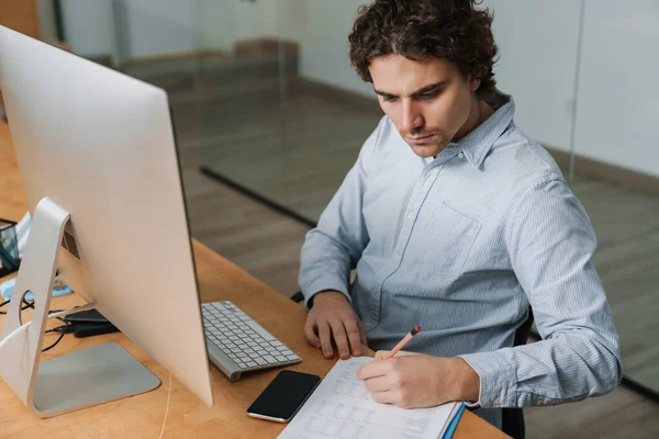 有信心的年轻企业家坐在写字台前 在电脑上工作 注意到 — 图库照片