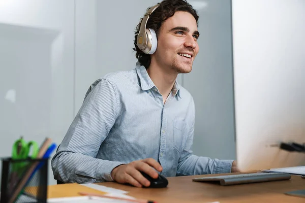 Kaukázusi Fiatal Boldog Üzletember Fülhallgatóban Mosolyog Miközben Dolgozik Számítógép Irodában — Stock Fotó