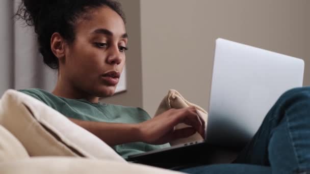 Fokusert Afroamerikansk Kvinne Bruker Datamaskinen Sin Mens Hun Sitter Sofaen – stockvideo