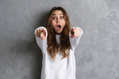 Gri arka planda izole edilmiş kamerayı gösteren oldukça heyecanlı genç bir kadın.