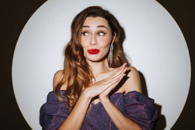 Güzel, heyecanlı, çekici bir kadın. Kokteyl elbisesi ve aksesuar giymiş. Sahne ışıkları altında poz veriyor.