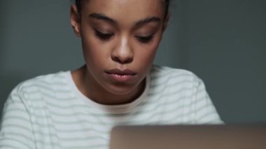 İşine odaklanmış bir Amerikalı kadın ofiste dizüstü bilgisayarını kullanarak çalışıyor.