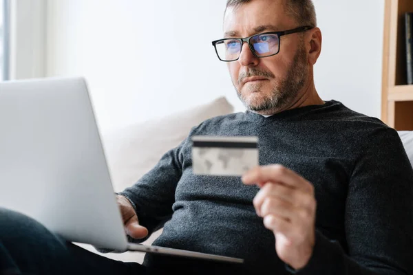 Ernsthafter Erwachsener Unrasierter Mann Benutzt Kreditkarte Während Hause Mit Laptop — Stockfoto