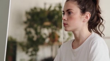 Yorgun kadının yan görüntüsü monitöre bakıyor ve ofiste otururken elleriyle başını dinlendiriyor.