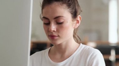 Bilgisayarda bir şey arayan ve ofiste otururken dudağını ısıran mutlu kadın.