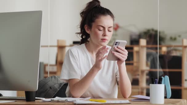 Mujer Positiva Hojeando Algo Teléfono Mientras Está Sentada Oficina — Vídeo de stock