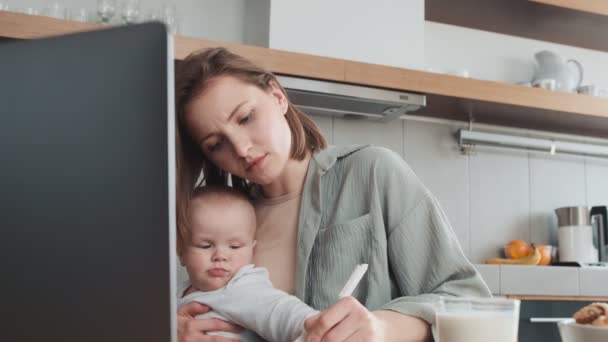 Madre Concentrada Escribiendo Algo Sosteniendo Pequeño Niño Sus Brazos Mientras — Vídeos de Stock