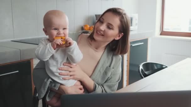 Uśmiechnięta Mama Trzymająca Swoje Szczęśliwe Dziecko Zabawką Ramionach Siedząc Przed — Wideo stockowe