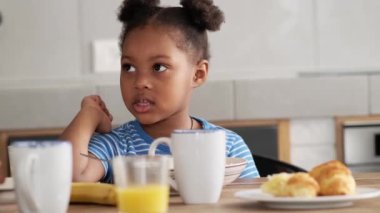 Küçük Afrikalı bir kız kahvaltıya bakıp duruyor.