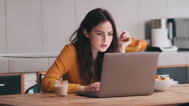 Skoncentrowana Kobieta Patrzy Ekran Laptopa Prostuje Włosy Siedząc Kuchni — Wideo stockowe