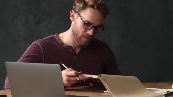 Ein Konzentrierter Mann Mit Brille Blickt Ein Notizbuch Mit Einem — Stockvideo