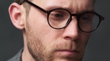 Düşünceli bir adamın bir şeye bakıp gözlüğünü çıkardığı yakın plan görüntüsü.