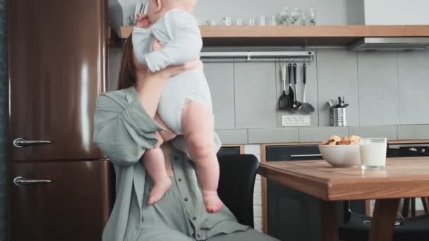 Una Mamá Sonriente Sosteniendo Pequeño Bebé Mientras Está Sentada Cocina — Vídeo de stock