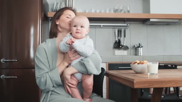 Una Mamá Besando Pequeño Niño Sonriente Abrazándolo Mientras Está Sentada — Vídeos de Stock