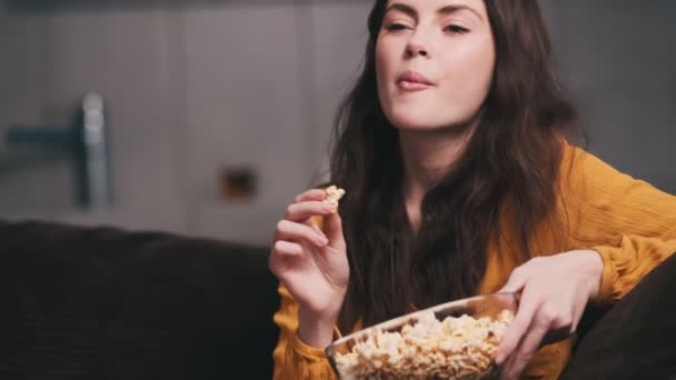 Eine Lächelnde Frau Isst Popcorn Und Beobachtet Etwas Während Sie — Stockvideo