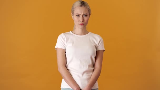 一位满脸皱纹的金发亚洲女人 身穿T恤 站在一家橙色工作室里 双手交叉 没有任何动作 — 图库视频影像