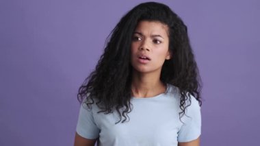 Tişörtlü kayıp bir Afrikalı kadın mor bir stüdyoda dikilirken uzakta birini arıyor.