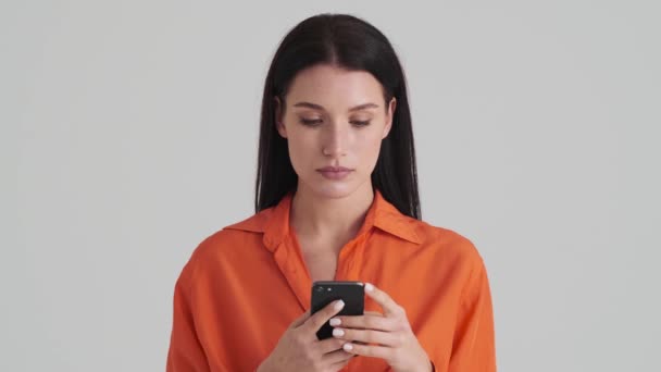 Soustředěná Žena Používá Svůj Smartphone Stojí Izolovaný Přes Šedou Stěnu — Stock video
