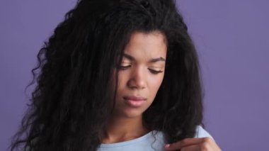 Mor stüdyoda dikilirken kırılan uçlara bakan huysuz Afrikalı bir kadının yakın çekimi.