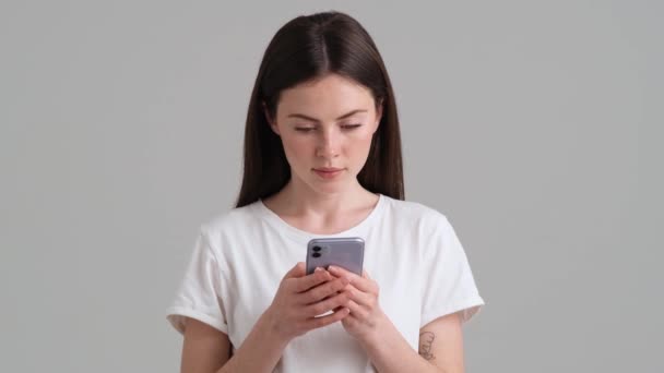 Een Lachende Vrouw Draagt Basic Shirt Gebruikt Haar Smartphone Geïsoleerd — Stockvideo