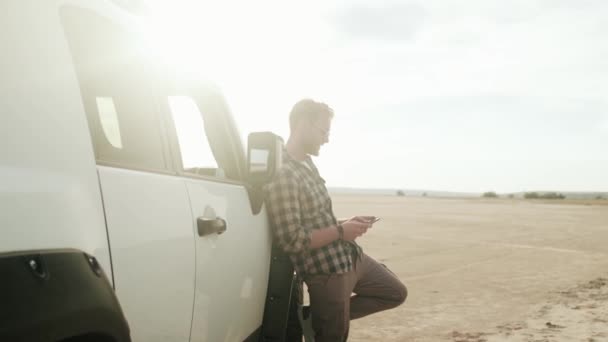 Homem Loiro Relaxado Está Usando Seu Smartphone Perto Carro Natureza — Vídeo de Stock