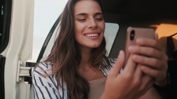 Uma Mulher Bonita Está Usando Seu Smartphone Enquanto Está Sentada — Vídeo de Stock