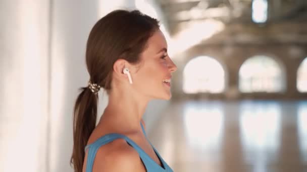 Una Vista Lateral Una Mujer Sonriente Con Auriculares Está Caminando — Vídeos de Stock