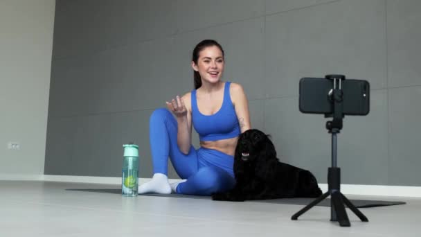 Positiv Idrottskvinna Spelar Video Sport Sitter Yogamattan Med Sin Hund — Stockvideo
