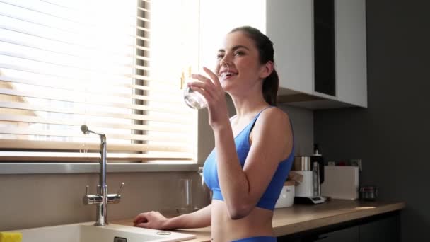 一位漂亮的女士正站在厨房里喝着一杯清水 — 图库视频影像