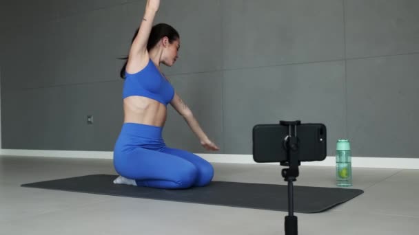 Uma Esportista Focada Está Gravando Vídeo Enquanto Faz Alongamento Sentado — Vídeo de Stock