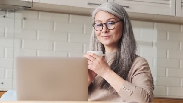 Egy Elégedett Idős Laptopját Nézi Otthon Konyhában — Stock videók