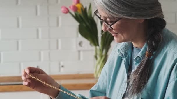 Pleased Elder Woman Making Hand Made While Holding Golden Chain — Stock Video