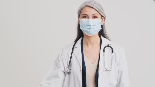 Uma Médica Idosa Confiante Usando Máscara Protetora Médica Está Mostrando — Vídeo de Stock