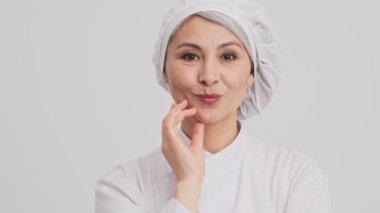 Pozitif kıdemli bir aşçı kadın bir şey düşünüyor ve sonra parmağını kaldırıp stüdyodaki gri duvarın üzerinde tek başına duruyor.