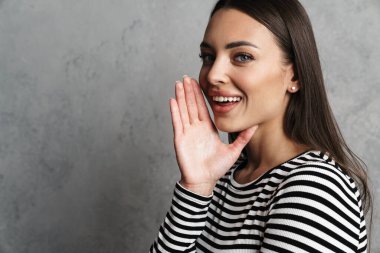 Gülümseyen çekici bir kadın Gri arka plandan izole edilmiş birini arıyor