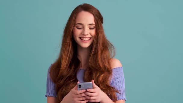 Uma Mulher Sorrindo Está Usando Seu Smartphone Isolado Sobre Parede — Vídeo de Stock