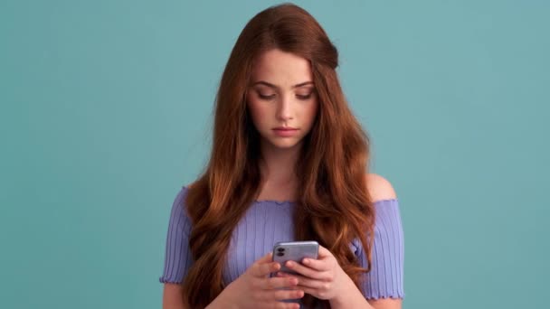 Een Gelukkige Vrouw Gebruikt Haar Smartphone Geïsoleerd Een Blauwe Muur — Stockvideo