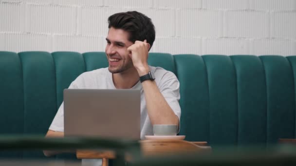 Egy Nevető Fiatalember Pólóban Aki Oldalra Néz Miközben Laptop Előtt — Stock videók