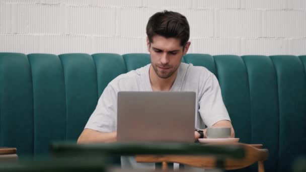 Concentrated Young Man Looking Something Laptop While Sitting Table Cup — Stock Video