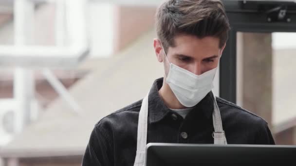 Barista Masculino Concentrado Uma Máscara Protetora Descartável Olhando Para Baixo — Vídeo de Stock