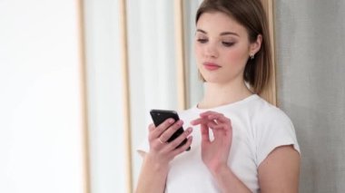 Çekici bir kadının yakın plan görüntüsü dairelerin içinde dururken akıllı telefonunu kullanıyor.