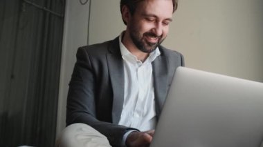 Ofis takım elbiseli mutlu adamın dairedeki dizüstü bilgisayara bir şey yazışının yakın görüntüsü.